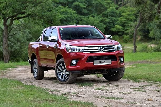 Red Toyota Hilux pickup truck on dirt road