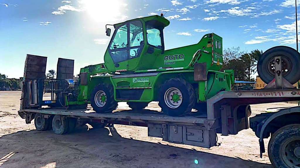 Green Merlo telehandler equipment on a flatbed trailer
